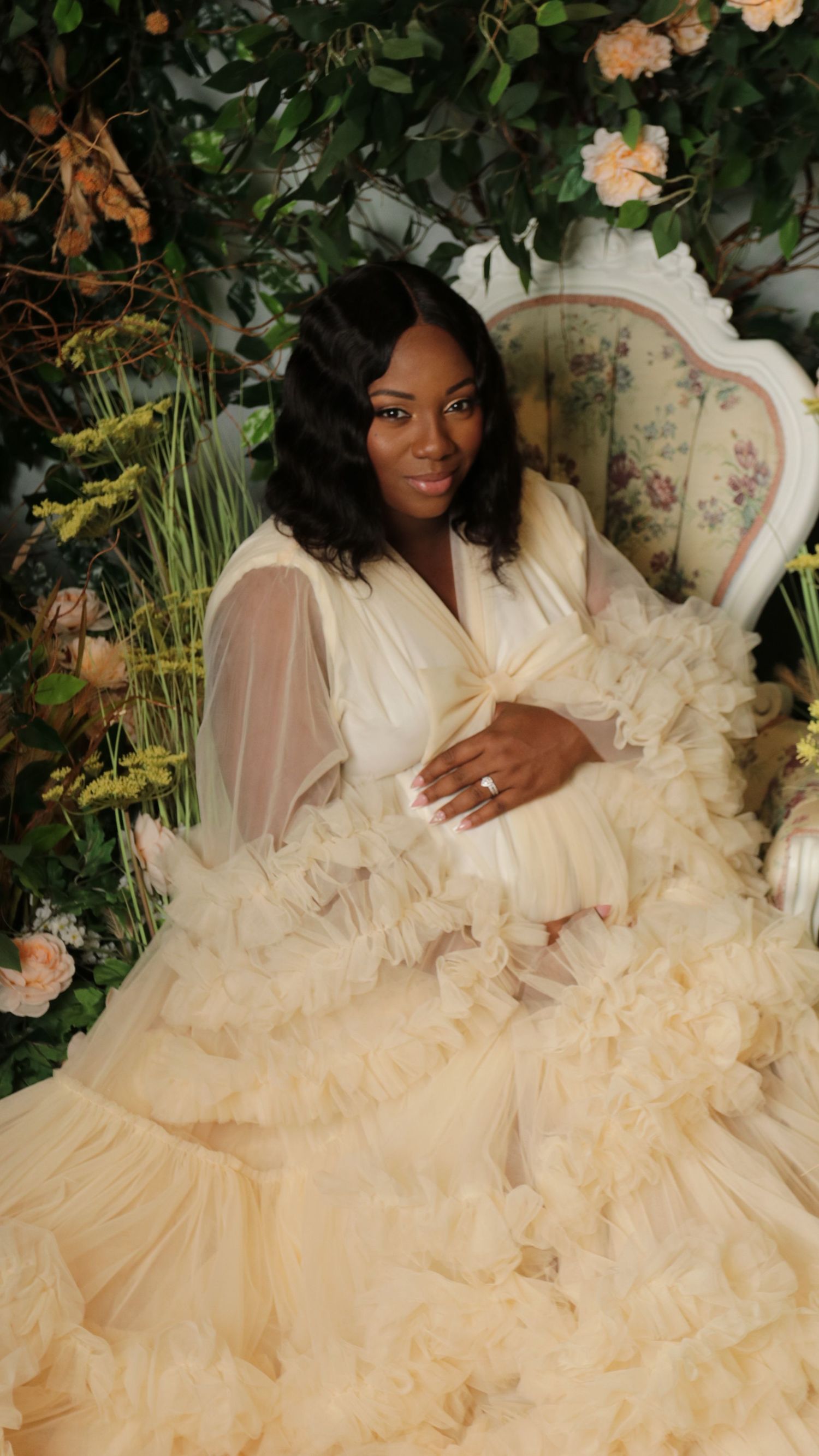 Elegant bridal portrait with cream ruffled gown in garden setting.