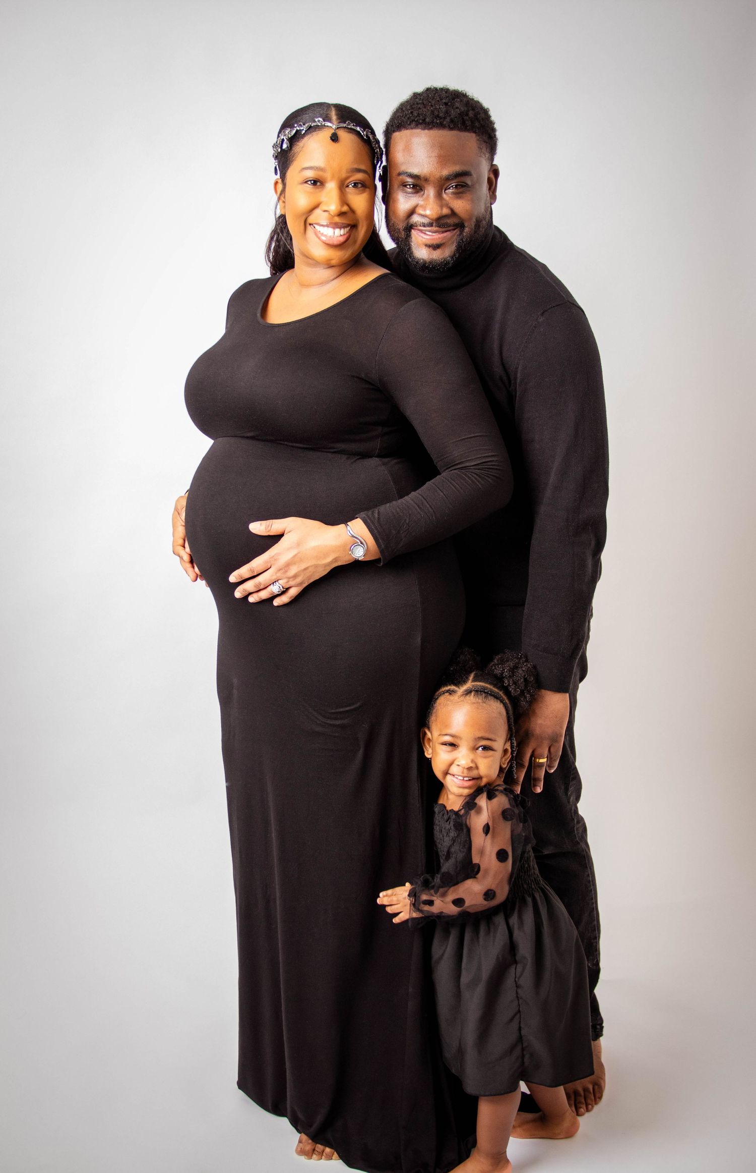 Family portrait session with coordinating black outfits in studio setting.