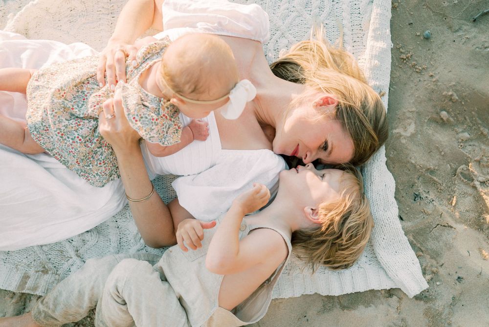A tender moment between parent and child laying on a blanket at the beach.