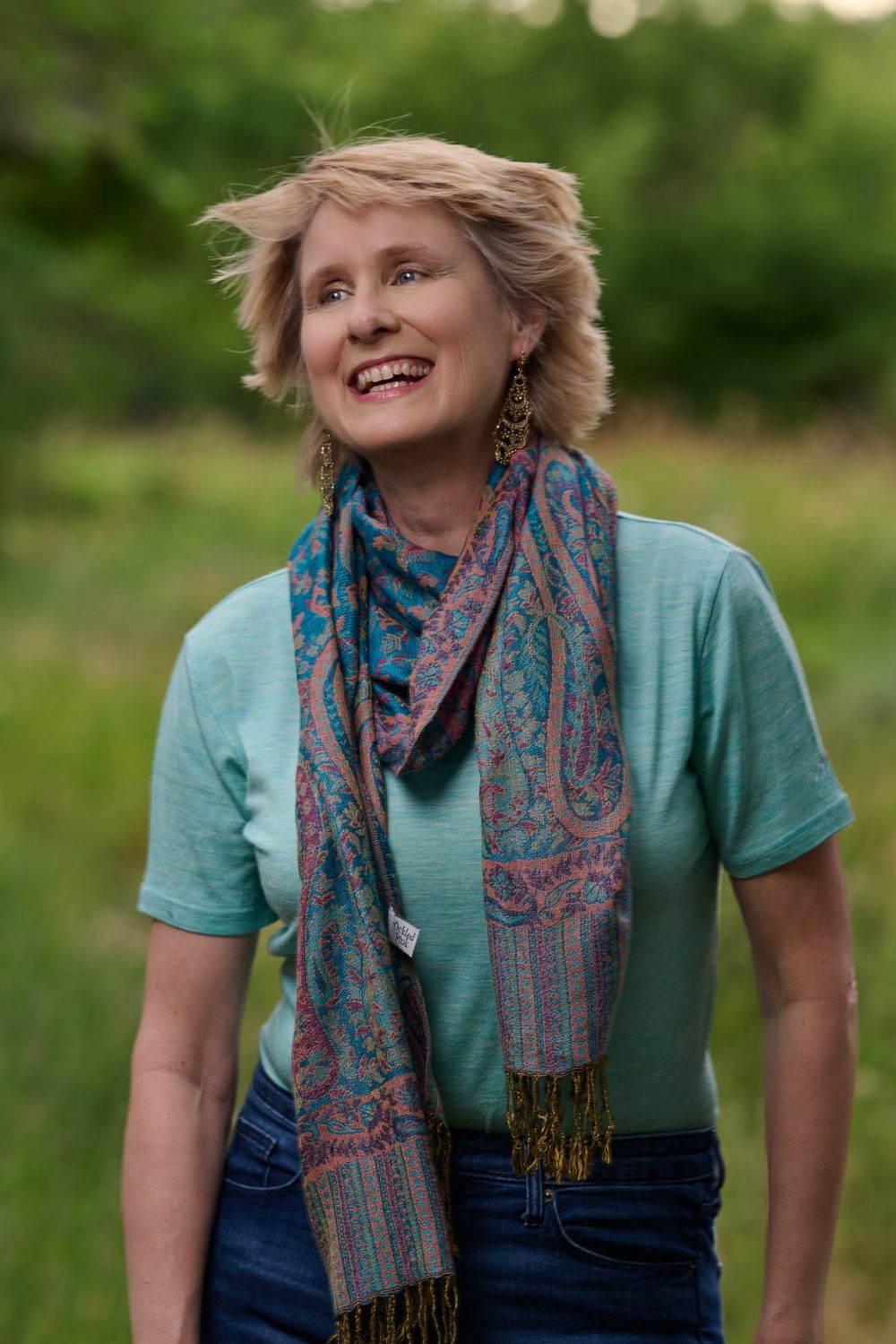 A series of portrait shots showing someone in a teal shirt and colorful patterned scarf outside in a grassy setting.
