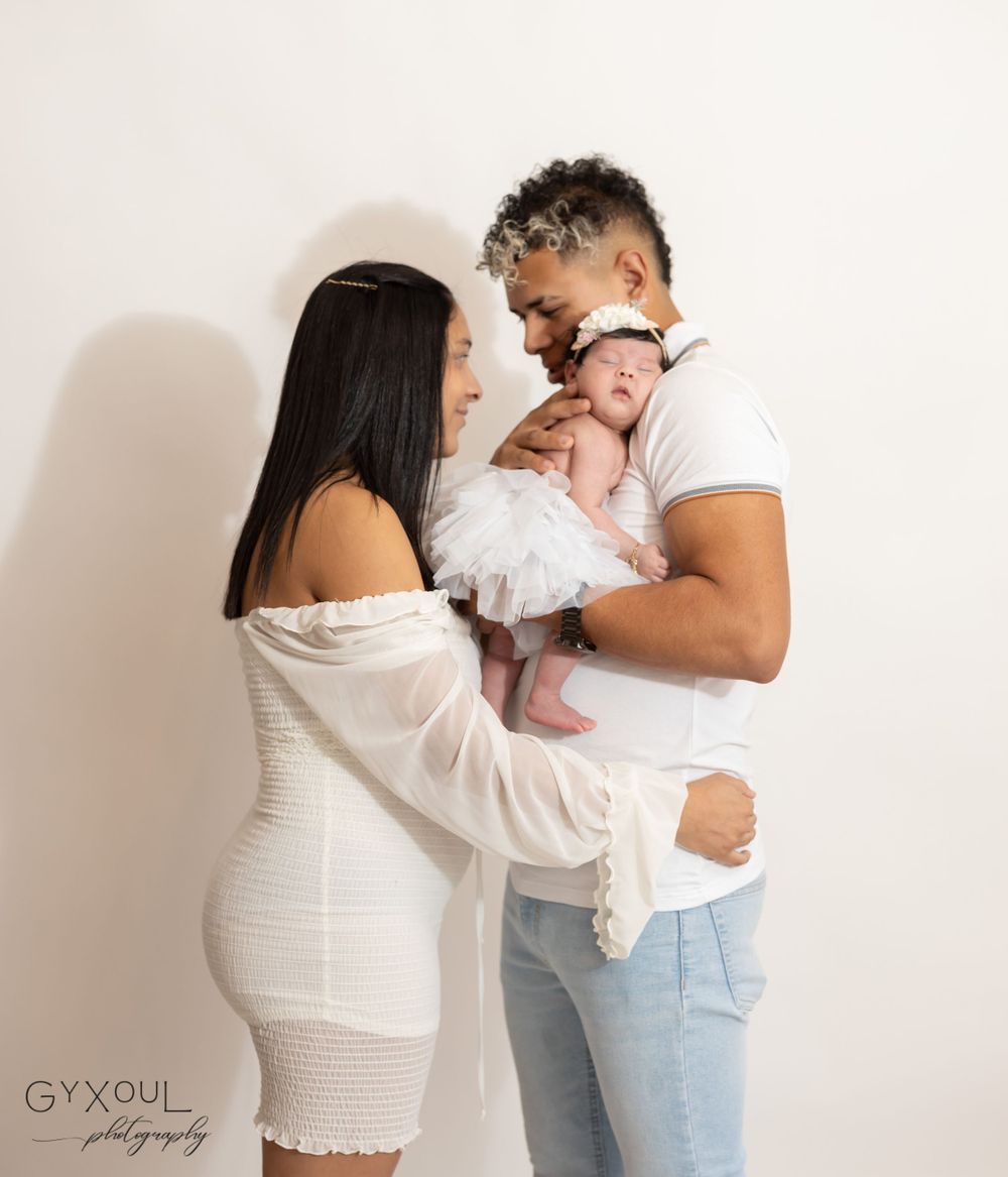 Intimate family portrait against white background with baby in white tulle outfit.