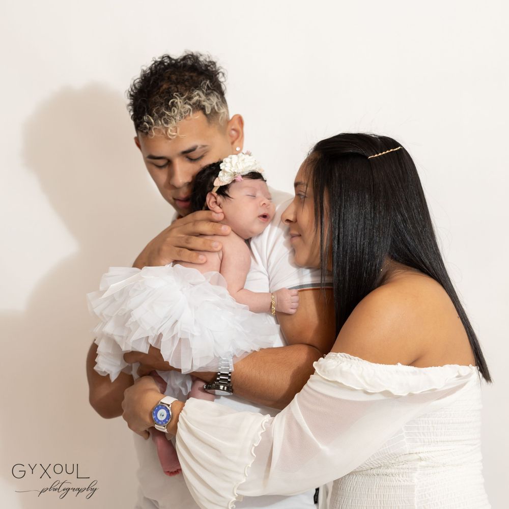 Family portrait showing tender moment with baby in white tulle dress.