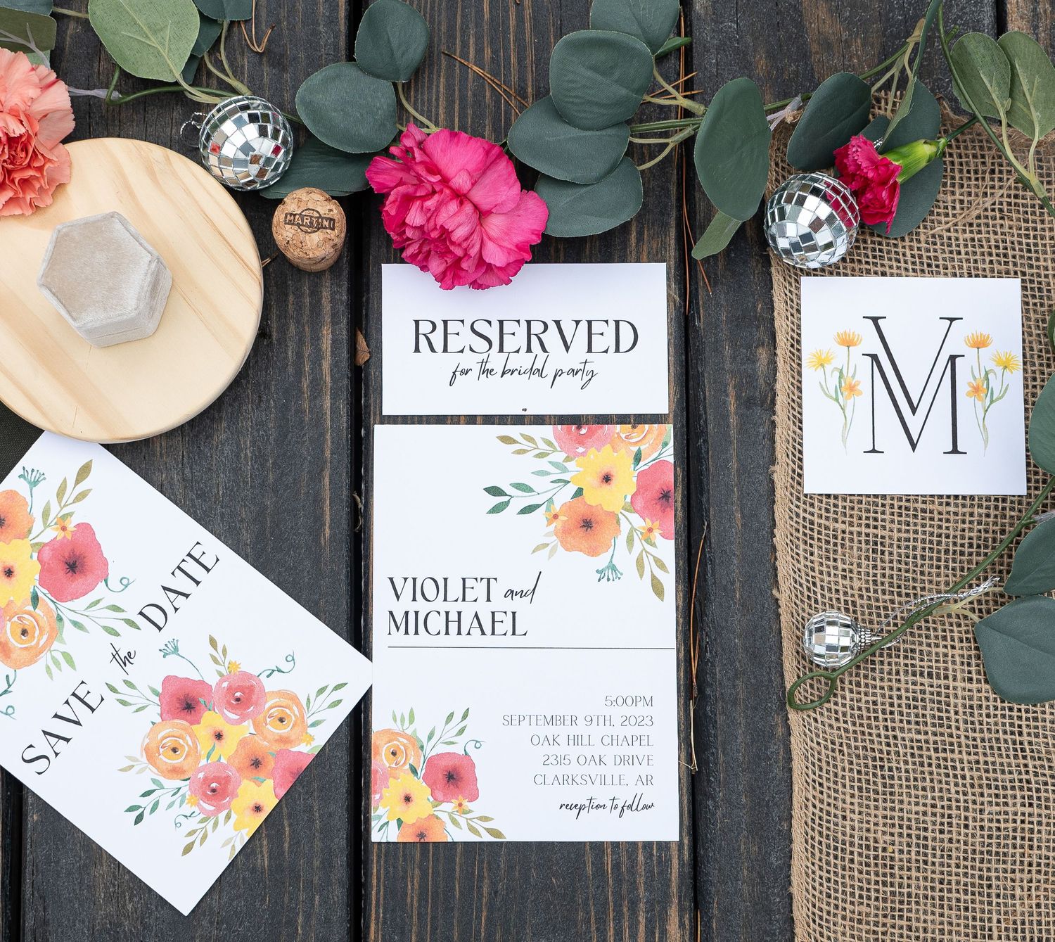 Elegant floral wedding stationery suite with save the date, invitation, and monogram card on dark wood.