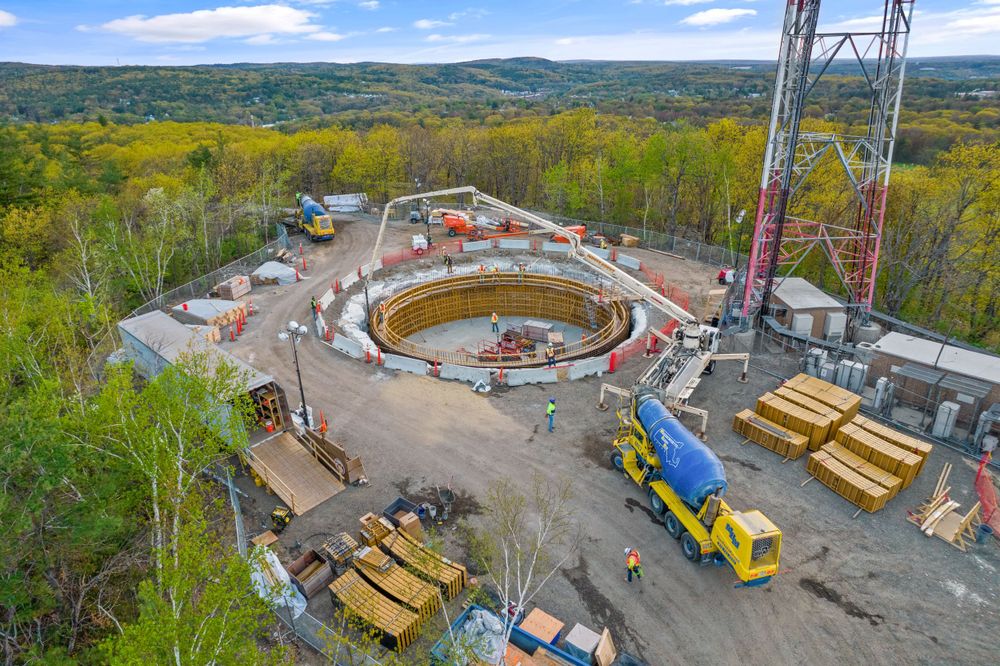 Aerial view of circular construction site surrounded by autumn forest.