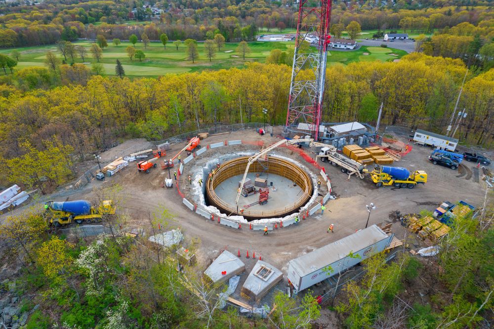 Bird's eye view of round concrete foundation with construction equipment and vehicles.