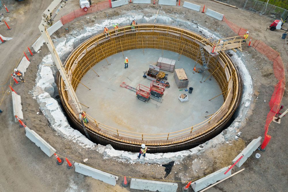 Overhead view of circular foundation construction with concrete formwork and equipment in center.