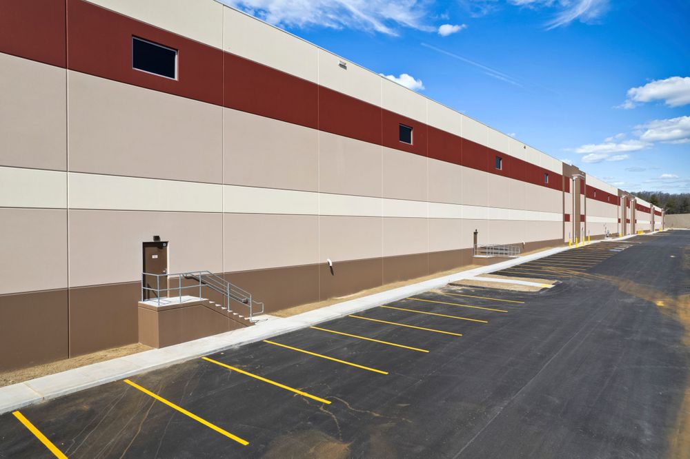 Exterior of modern industrial building with brown and beige walls and freshly painted parking spaces.