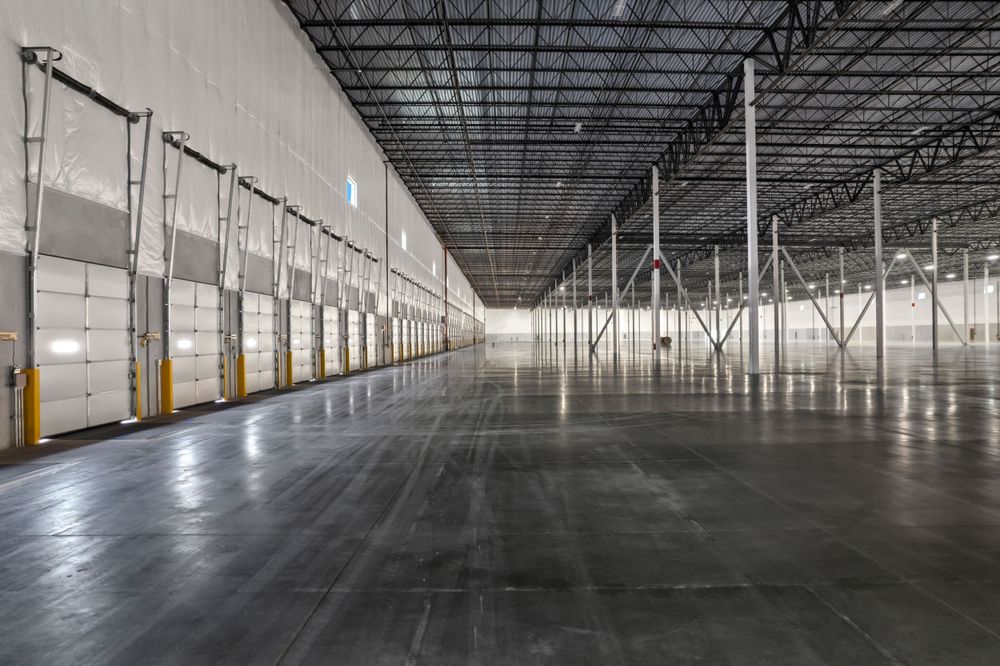 Interior view of empty warehouse showing loading dock doors and polished concrete floor.
