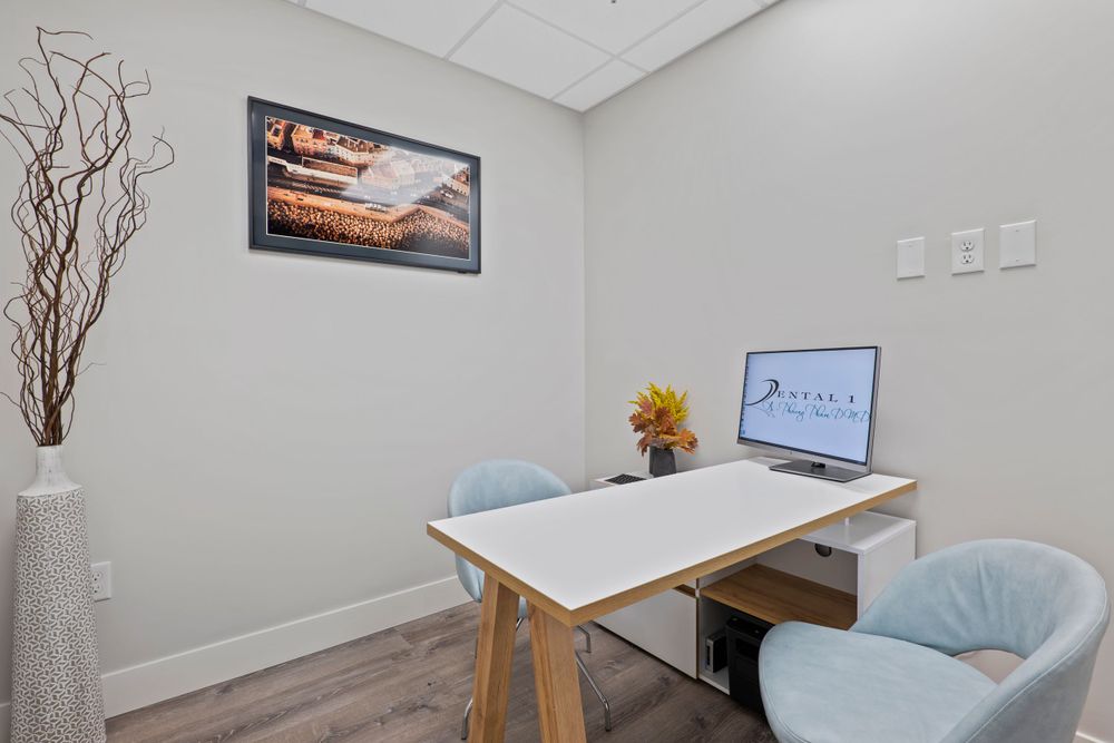 Contemporary office space with white desk, blue chairs, and nature-themed wall art.