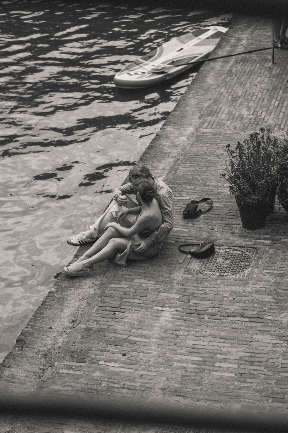 A couple lying together on a brick surface near water in a romantic pose.