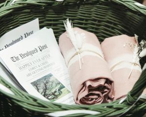 Wedding programs and pink roses arranged in a woven basket.