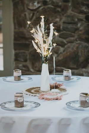 Elegant table setting with white milk glass vase centerpiece and dessert plates with decorative borders.