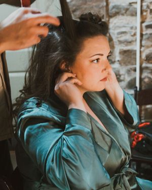 Getting ready scene showing preparation with teal silk robe against stone wall background.