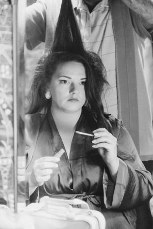 Classic black and white portrait of a woman getting ready at a vanity mirror.
