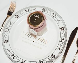 Elegant place setting with decorative plate and table number at formal wedding reception.
