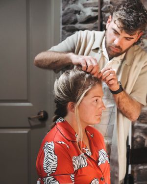 Hair stylist working on bride's updo hairstyle before the wedding ceremony.