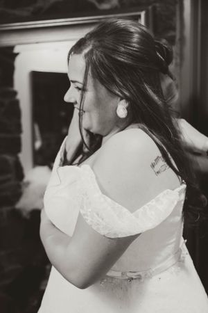 A black and white photo of a bride in an off-shoulder wedding dress with her hair in an updo.