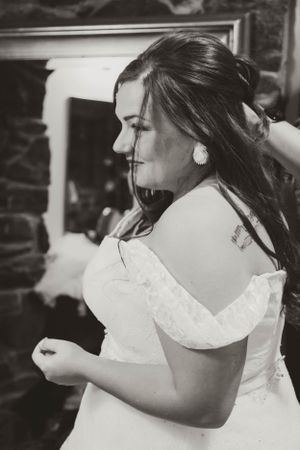 A black and white portrait of a bride in an off-shoulder wedding dress with delicate details.