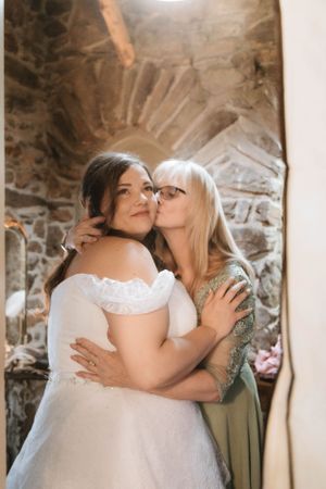 Two people sharing an intimate moment in a rustic stone archway during a wedding celebration.