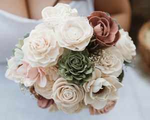 A romantic wedding bouquet featuring cream, dusty rose, and sage green roses in a vintage style arrangement.