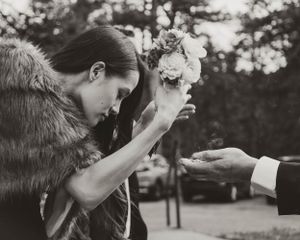 Black and white photo of wedding ceremony moment with fur wrap and floral details.