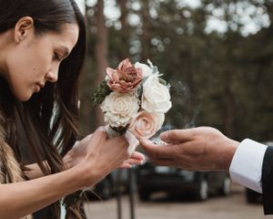 A woman smelling a beautiful bouquet of pink and white roses while someone holds it.