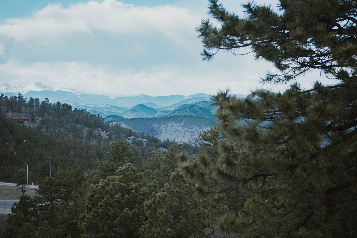 Scenic mountain landscape with layered blue ridges and evergreen trees framing the misty vista in the distance.