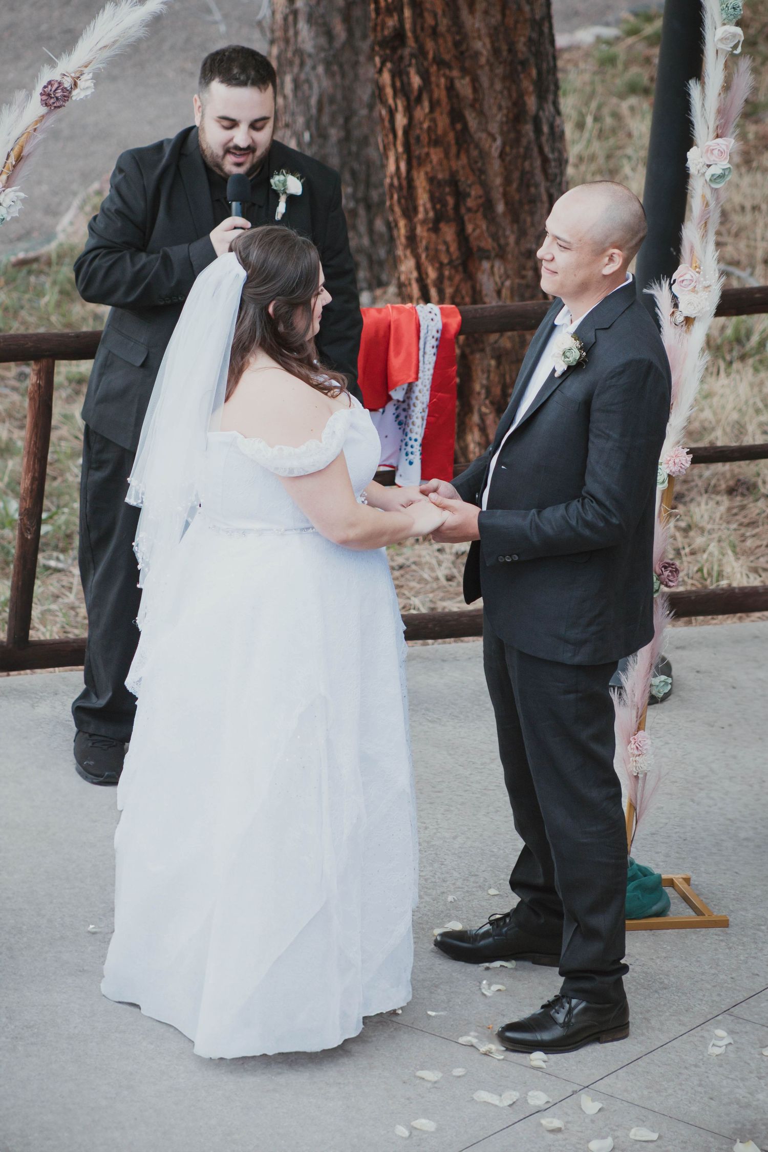 Outdoor wedding ceremony with couple exchanging vows while officiant presides.