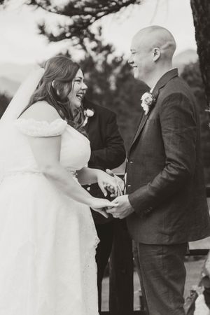 A black and white photo of a joyful wedding ceremony moment between a bride and groom.
