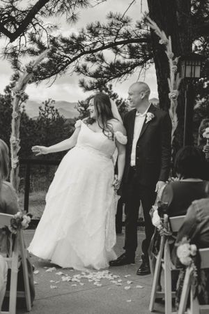 A joyful wedding couple sharing a moment during their outdoor ceremony with pine trees in the background.