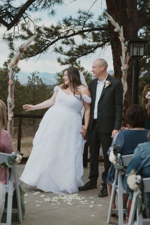 A couple celebrates after their wedding ceremony on a mountain overlook with guests seated behind them.
