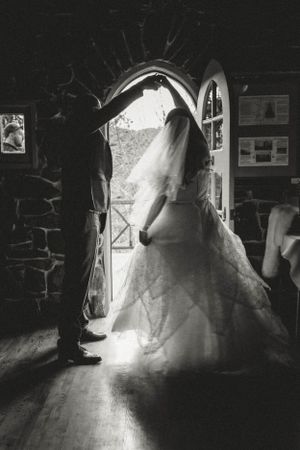 A silhouette of a bride in a doorway of a stone building with dramatic lighting.