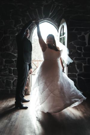 A dramatic backlit wedding photo showing a couple posing in a gothic stone doorway.