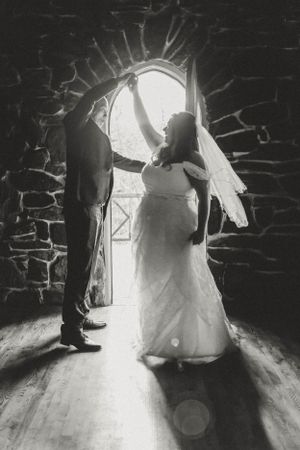 A backlit wedding couple standing in a dramatic stone doorway creating beautiful shadows.