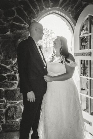 A black and white photo of a couple standing in an arched stone doorway.