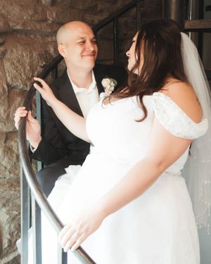 A joyful wedding moment between newlyweds sharing a laugh on a stone staircase.