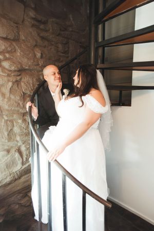 A couple sharing an intimate moment on a staircase in a stone building.