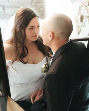 An intimate moment between newlyweds during their wedding ceremony against a stone wall backdrop.