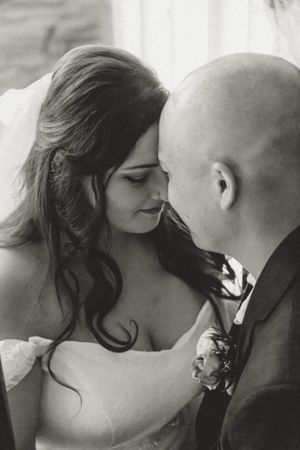 Intimate black and white wedding portrait showing tender romantic moment between newlyweds.