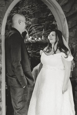 A black and white wedding photo showing a couple in an arched stone doorway during their ceremony.