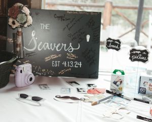 Wedding guest book table setup with Polaroid camera and decorative chalkboard sign.