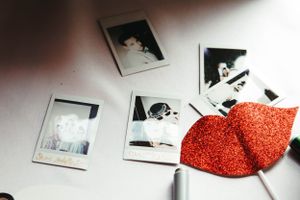 Polaroid photographs scattered on white surface with red glittery heart decoration.