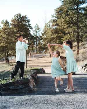 People in matching mint-colored outfits dance and pose playfully on a mountain trail.