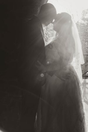 A silhouetted couple shares an intimate moment in dramatic backlighting during their wedding ceremony.