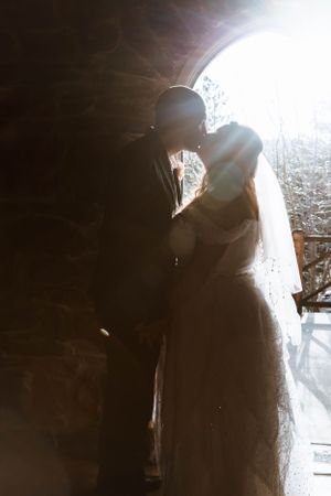 An artistic silhouette of newlyweds sharing an intimate moment in backlit natural lighting.