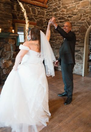 A couple shares their first dance in a rustic stone-walled room during their wedding celebration.