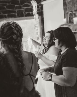 A candid black and white photo showing wedding preparation moments with the bride and others getting ready indoors.