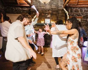 People dancing and celebrating at a rustic indoor venue with stone walls and wooden beams.
