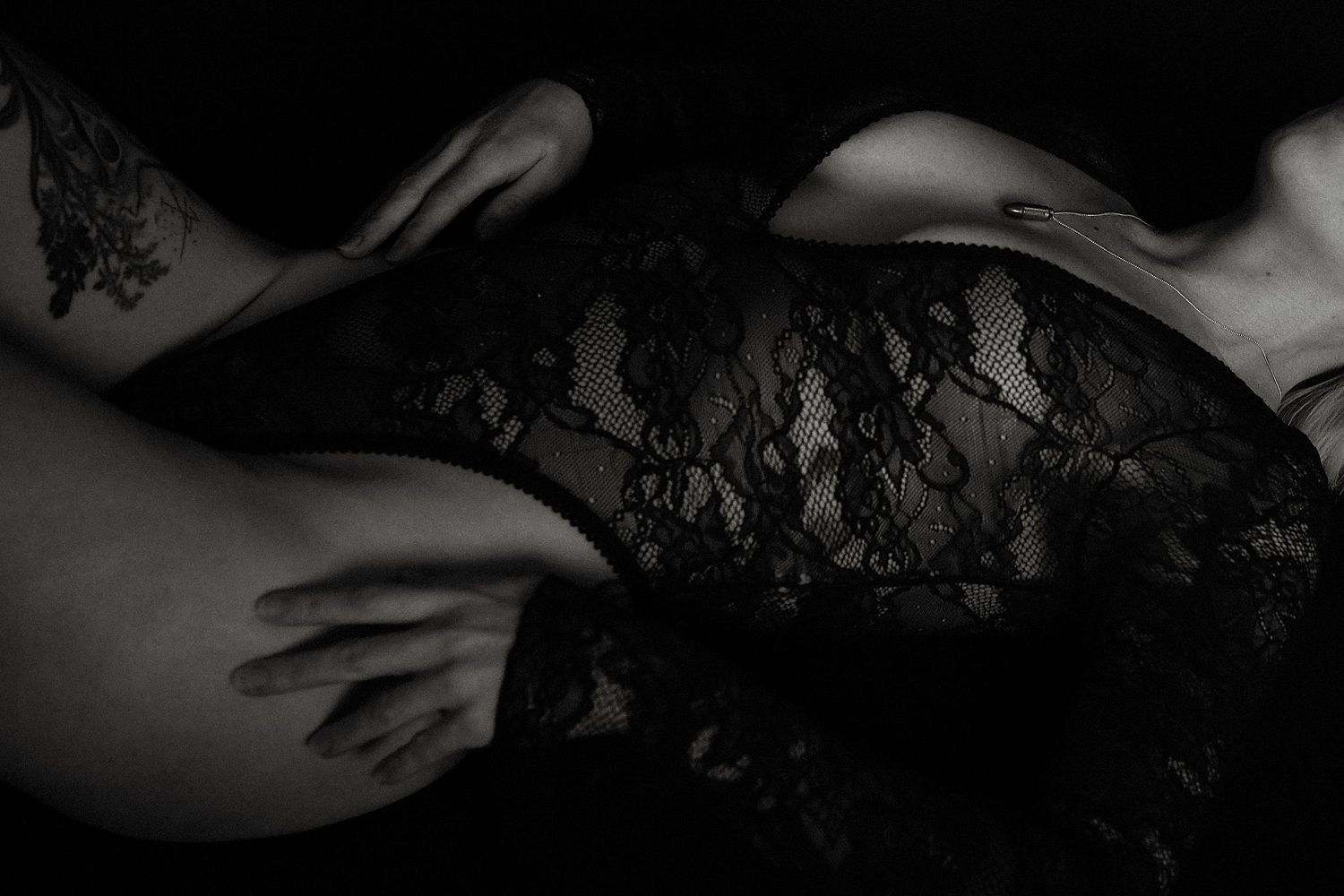 Artistic black and white photo of lace fabric against skin.