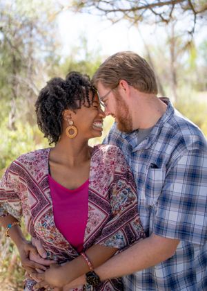 Engaged young couple sharing a romantic moment outdoors under a tree.